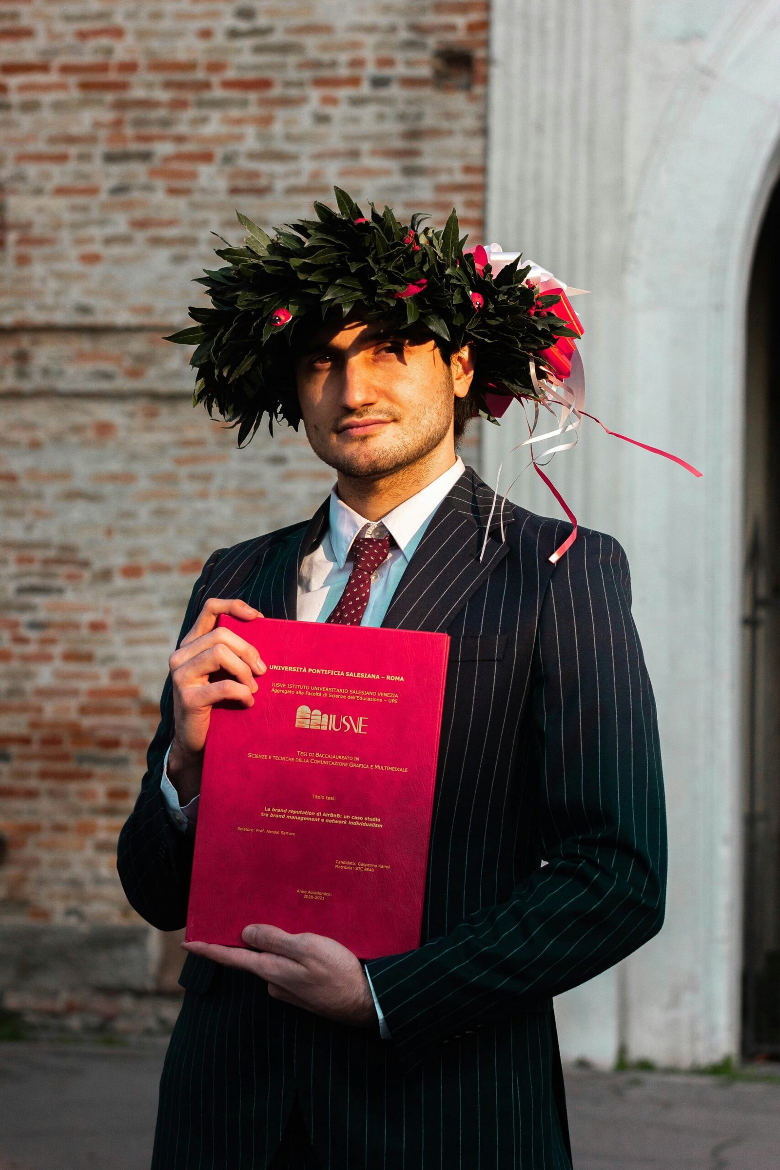 man in black suit holding red book